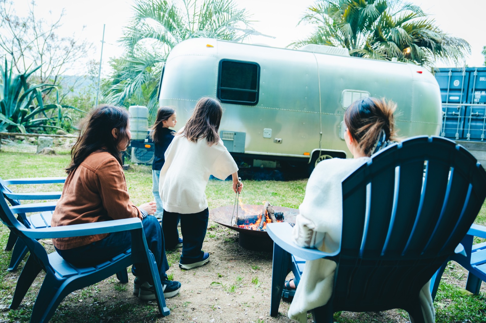 エアストリームの前で庭と火を囲む貸切サイト
