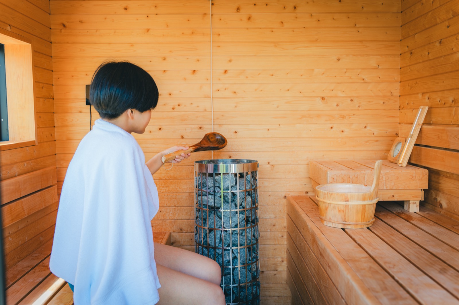 木のサウナ室でロウリュをする